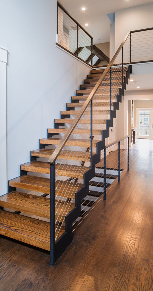 Zig zag double stringer straight sair iwth wood treads in a main entry with wood floors.