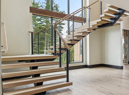 Modern floating stairs with the Ithaca cable railings system, wood stair treads and handrailing featured in a rustic great room