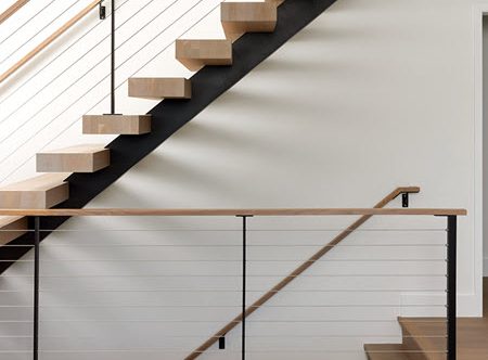 Floating stairs that feature wood treads and cable railings. The treads ar uniquely made to appear to slice into the stair stringer.
