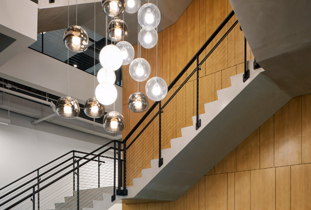 Light wood paneling contrast with the white  stairs and black cable railings offering a modern aesthetic to this business lobby.