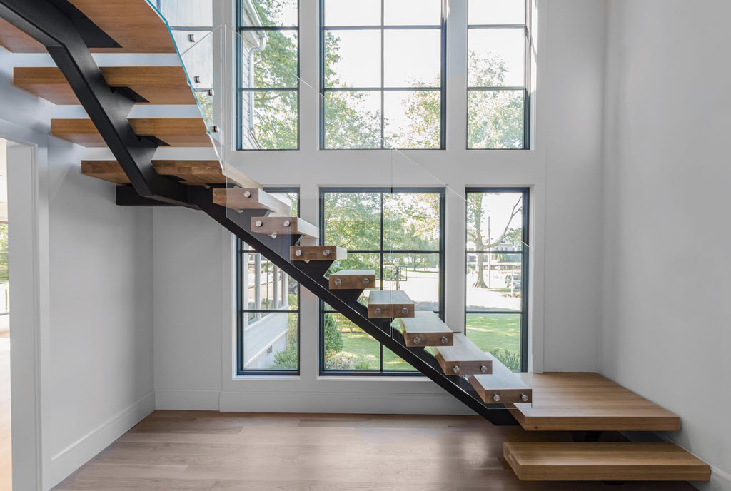 Window wall as a feature wall adjacent to a black mono stringer floating staircase with wood treads and glass railing