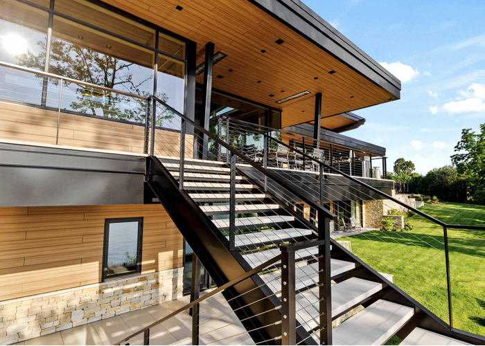 Exterior double stringer stairs with lime stone treads and cable railing system by Keuka Studios on a modern lake house