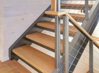 Wood handrail detail on this landing with stainless steel cables 