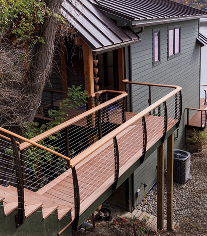 Bridge to lake house entrance wrapped with curved cable railings fascia mounted