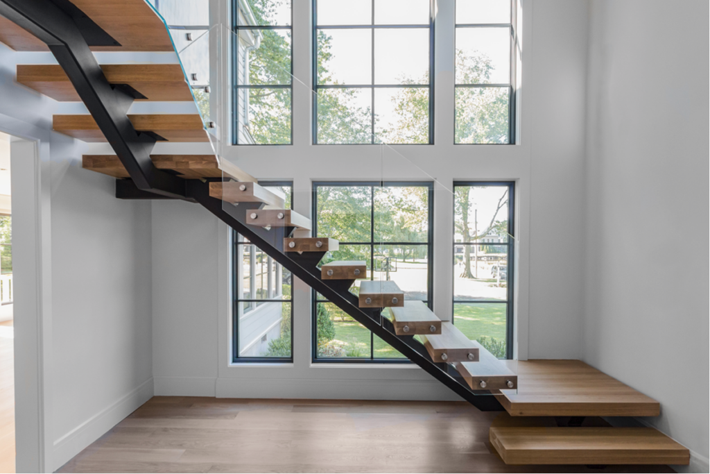 Single stringer floating stair with glass railings and wood treads in an open space with a window wall.