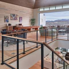 Metal framed glass railing with wood top rail on interior of modern home. The railing transitions up th e stairs and around the living room landing